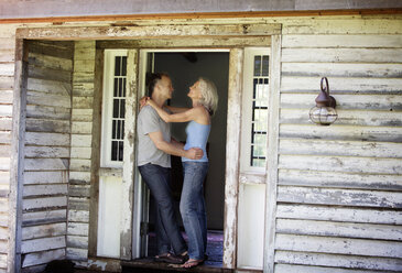 Side view of romantic senior couple standing at doorway - CAVF13713