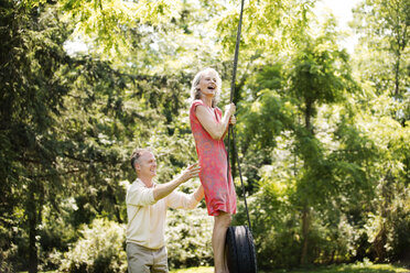 Happy senior couple playing on swing at park - CAVF13725