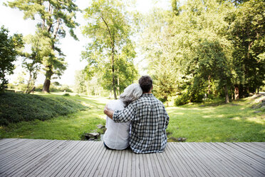 Rear view of couple sitting with arm around at porch - CAVF13731