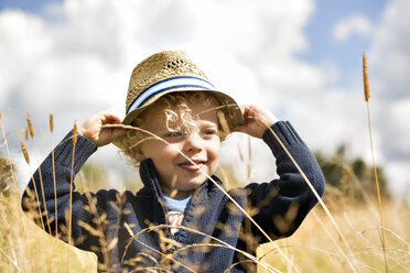 Close-up of happy boy wearing hat standing amidst plants - CAVF13758