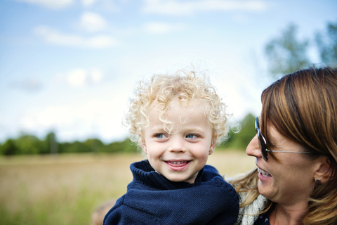 Nahaufnahme einer glücklichen Mutter mit lächelndem Sohn auf einem Feld, lizenzfreies Stockfoto