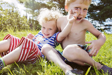 Portrait of happy siblings enjoying on grassy field - CAVF13774