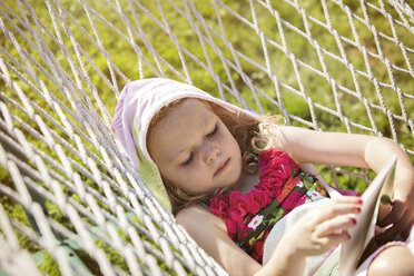 Girl reading book while lying in hammock - CAVF13776