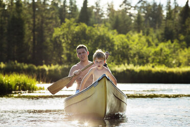 Lächelnder Vater beim Bootfahren mit seinem Sohn auf dem See - CAVF13781