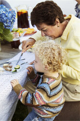 High angle view of grandmother feeding grandson on picnic table - CAVF13797