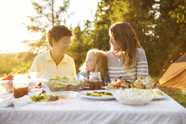 Mehrgenerationen-Familie beim Picknick am Tisch - CAVF13807