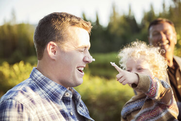 Son playing with father at picnic on sunny day - CAVF13812