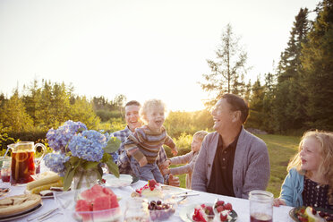 Fröhliche Familie am Picknicktisch an einem sonnigen Tag - CAVF13820