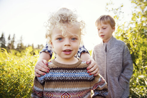 Porträt eines Jungen mit Geschwistern auf einem Feld - CAVF13821