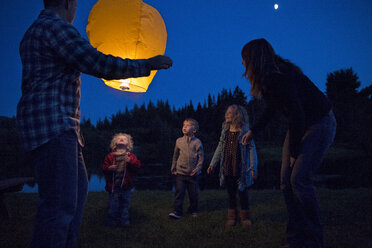 Niedriger Blickwinkel auf eine glückliche Familie mit beleuchteter Laterne auf einem Feld - CAVF13831