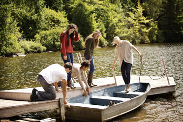 Freunde auf dem Pier bei einem Boot am See - CAVF13844