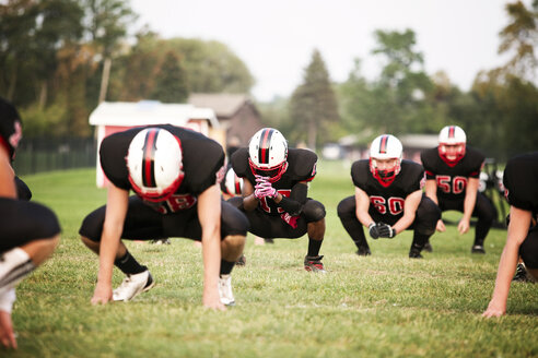 American-Football-Spieler, die auf einer Wiese hocken - CAVF13853