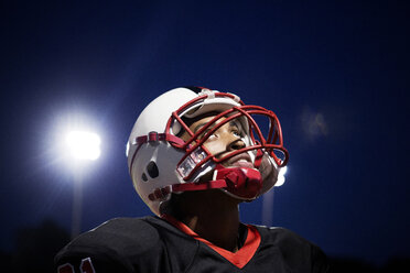 American-Football-Spieler im Teenageralter blickt auf ein beleuchtetes Feld - CAVF13864