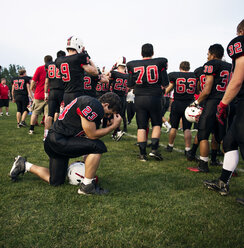 American football team standing on grassy field against sky - CAVF13869