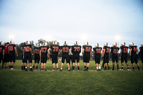 Rückansicht einer American-Football-Mannschaft auf dem Spielfeld gegen den Himmel, lizenzfreies Stockfoto