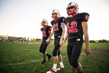 American-Football-Spieler, die sich an den Händen halten und auf einer Wiese laufen - CAVF13877