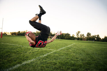 Junge springt mit American Football auf Spielfeld - CAVF13879