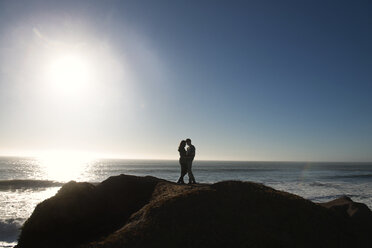 Paar steht auf einem Felsen am Meer gegen den Himmel an einem sonnigen Tag - CAVF13916