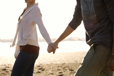 Couple holding hands while walking on beach - CAVF13919