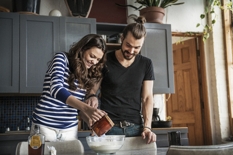 Glückliches junges Paar bereitet Essen auf dem Tisch zu Hause vor, lizenzfreies Stockfoto
