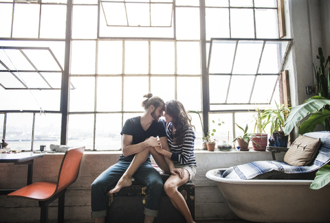 Junges Paar entspannt sich zu Hause am Fenster, lizenzfreies Stockfoto