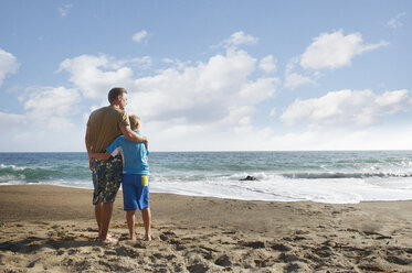 Vater und Sohn stehen am Strand gegen den Himmel - CAVF13978