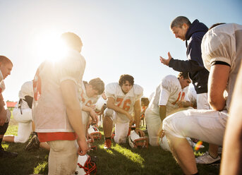 Selbstbewusster Trainer beim Training der Spieler auf dem American-Football-Feld an einem sonnigen Tag - CAVF14009