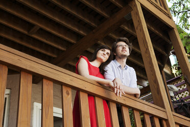 Niedriger Blickwinkel auf ein junges Paar, das am Geländer eines Balkons steht - CAVF14032