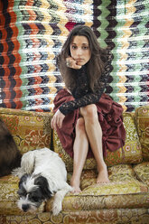 Porträt einer Frau mit Hund auf dem Sofa zu Hause - CAVF14039