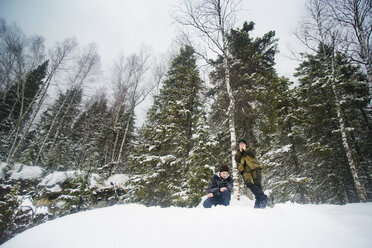 Low angle view of friends on snow covered field in forest - CAVF14049