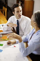 Business people discussing while sitting at desk in office - CAVF14077