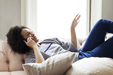 Woman talking on smart phone while relaxing at home - CAVF14088