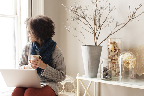 Frau mit Laptop-Computer, während sie zu Hause sitzt, lizenzfreies Stockfoto