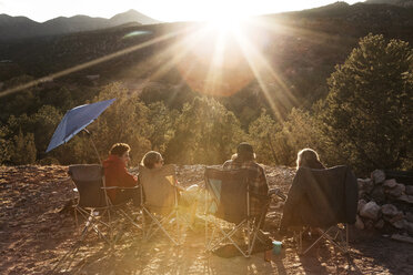 Freunde genießen beim Ausruhen auf dem Campingplatz gegen Bäume an einem sonnigen Tag - CAVF14147