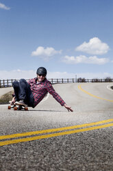 Man skateboarding on road against sky - CAVF14154