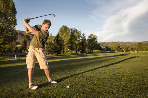 Golfer schwingt Golfschläger, während er auf einem grasbewachsenen Feld steht - CAVF14158