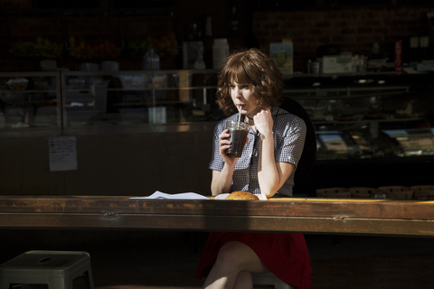 Frau schaut weg und trinkt Cola in einem Café, lizenzfreies Stockfoto