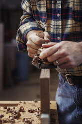 Mittelteil eines Arbeiters, der in einer Werkstatt ein Holzbrett spaltet - CAVF14383