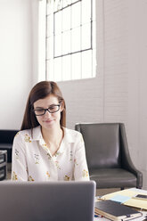 Selbstbewusste Geschäftsfrau mit Laptop im Büro sitzend - CAVF14409