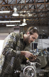 Serious mechanic working on machinery at auto repair shop - CAVF14427