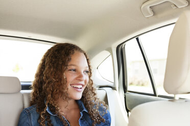 Happy teenager looking away while sitting in car - CAVF14484