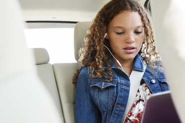 Niedriger Blickwinkel eines Teenagers, der im Auto sitzend Musik hört - CAVF14485