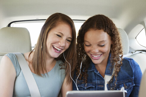 Glückliche Freunde, die im Auto sitzend Musik hören - CAVF14486