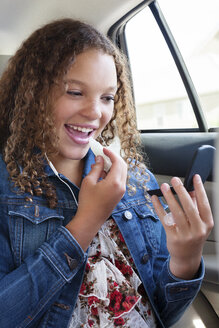 Teenager trägt Lippenbalsam auf, während er im Auto sitzt - CAVF14488