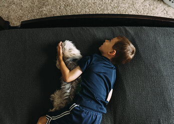 Draufsicht auf einen Jungen, der mit seinem Hund zu Hause auf dem Bett liegt - CAVF14494