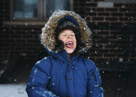 Fröhlicher Junge genießt den Schneefall, lizenzfreies Stockfoto