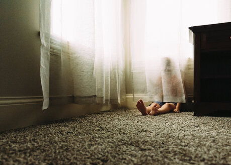 Verspielter Junge versteckt sich zu Hause hinter einem Vorhang - CAVF14506