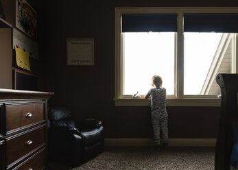 Rear view of boy looking through window - CAVF14521