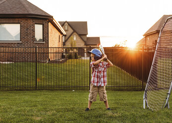 Junge spielt Baseball im Hinterhof bei Sonnenuntergang - CAVF14527
