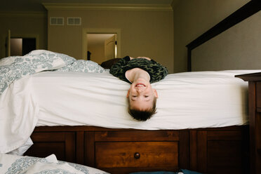 Portrait of happy boy lying on bed at home - CAVF14553